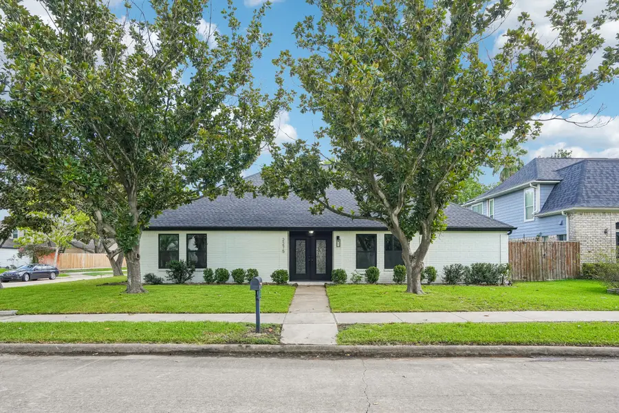 Before day to dusk conversion, a white-brick single-storey home photographed in flat overcast daylight with two large magnolia trees in the front yard